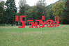 Wortskulptur Turmbau zu Babel (einer von drei Teilen) Drei großformatige Buchstabenskulpturen aus Holztafeln entlang der Wegstrecke durch den Park von Schloss Eggenberg, Graz 2003. Künstler: Christian Möller, Pete Conolly. Abhängig vom jeweiligen Standpunkt der Betrachter/innen fügen sich die abstrakten Tafelgruppen in einem Spiel mit Perspektive und Standortwechsel zu den lesbaren Worten »Turm« »zu« »Babel« zusammen. Bild: Thomas Born